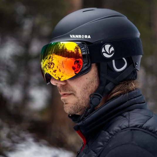 Person wearing a black ski helmet and goggles with vanrora branding, set against a snowy background.