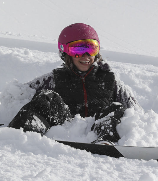 Person sitting in the snow with vanrora ski helmet and ski goggles.