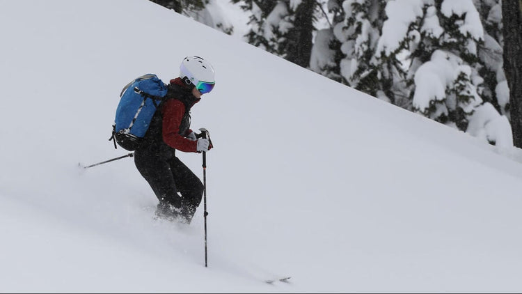 skier skiing down a snowy slope with trees