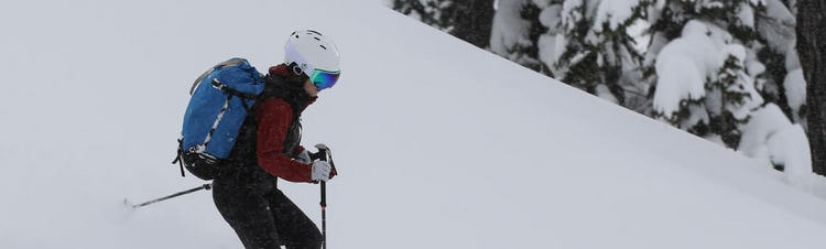 skier with vanrora ski helmet and gogles is skiing down a snowy slope 